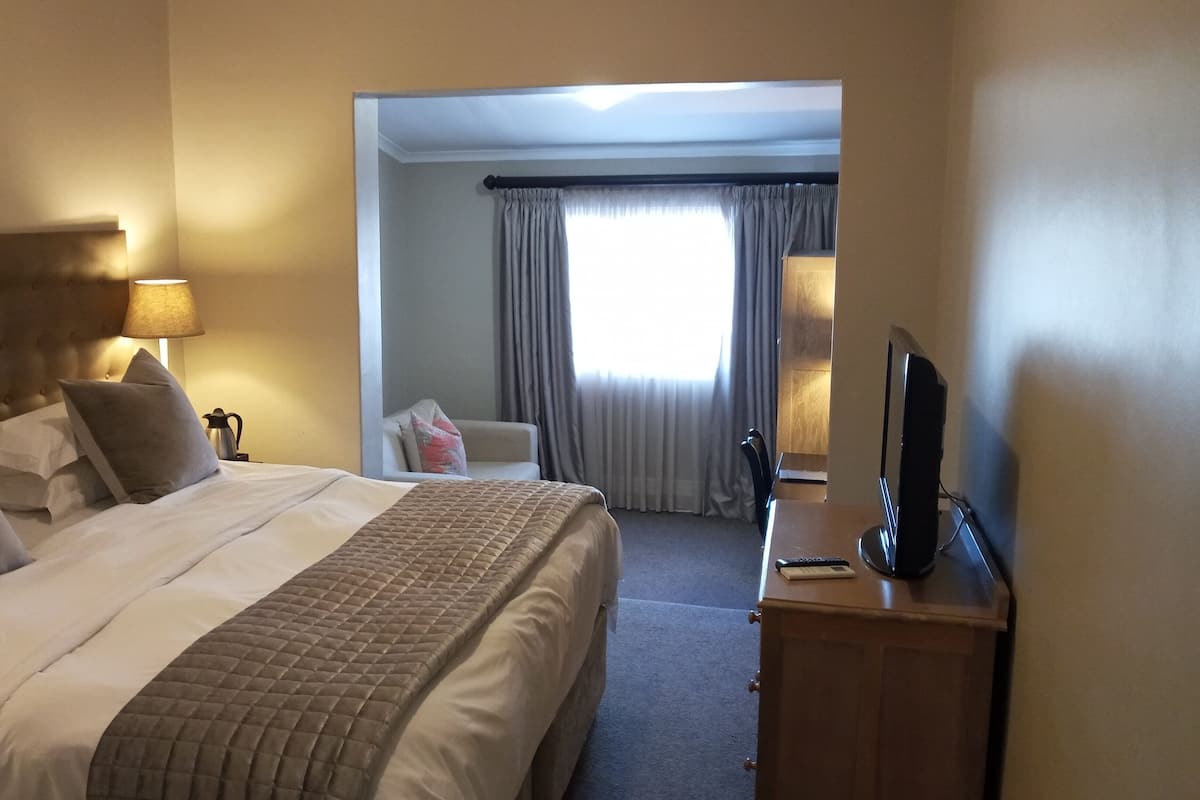 Ein Hotelzimmer mit einem großen Bett, einem Schreibtisch mit Fernseher und einem Sessel.