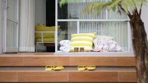 A set of wooden steps leading to a seating area with yellow cushions and pillows. - YATS Colony (Yogyakarta)