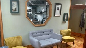 A room with a large octagonal mirror, two yellow armchairs, a grey sofa, and a small table with a laptop. - Paul Arthur's Restaurant and Rooms - Kircubbin (Portaferry)