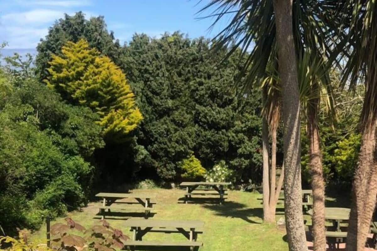 A park with picnic tables and a brick wall.