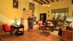 Una sala de estar acogedora con chimenea, un escritorio, una silla roja y un sofá.