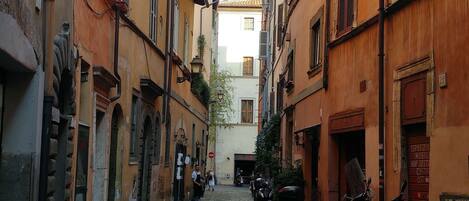 A cobblestone street flanked by historic buildings with arched doorways and traditional shutters.