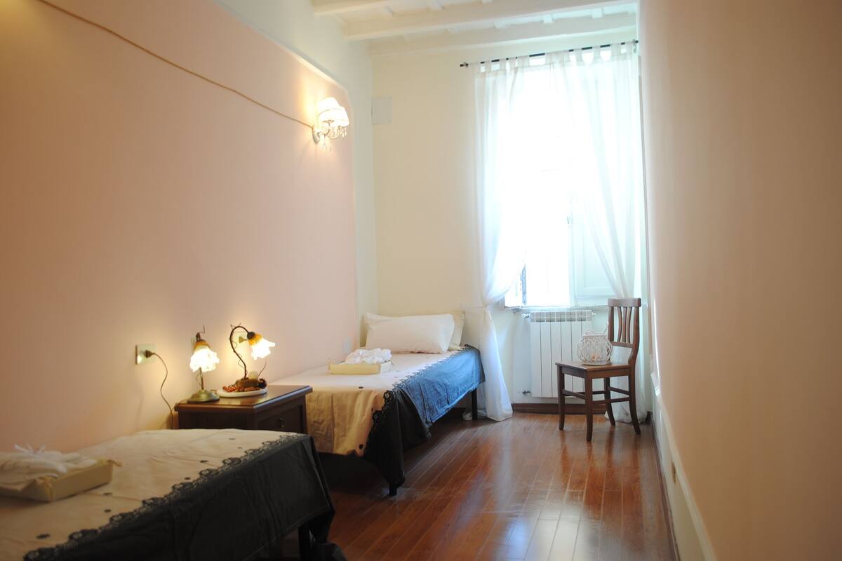 A bedroom with a bed, bedside tables, a chair, and a window with curtains.