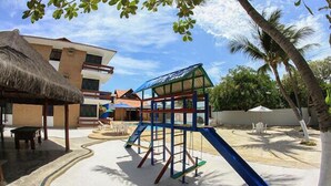 Un patio de juegos con tobogán, columpios y una estructura para escalar.
