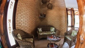 Habitación de esquina con pared de ladrillo, muebles de mimbre y una pequeña mesa con revistas.