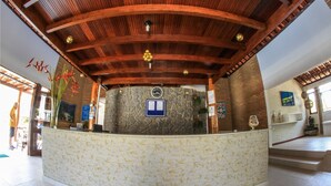 Una zona de recepción con pared de piedra, techo de madera y un reloj.