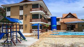 Un hôtel doté d’une piscine, d’un espace de jeux pour enfants et d’un grand bassin d’eau bleue.
