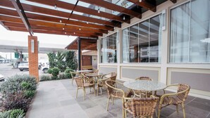 An outdoor patio with wicker furniture and a brick pillar. - Hotel Prata Villaggio (Nova Prata)