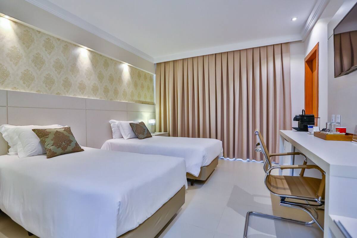 Een hotelkamer met twee bedden, een bureau, een stoel en een spiegel.