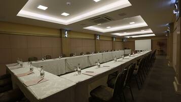 A conference room with a long table, chairs, and a projector screen.
