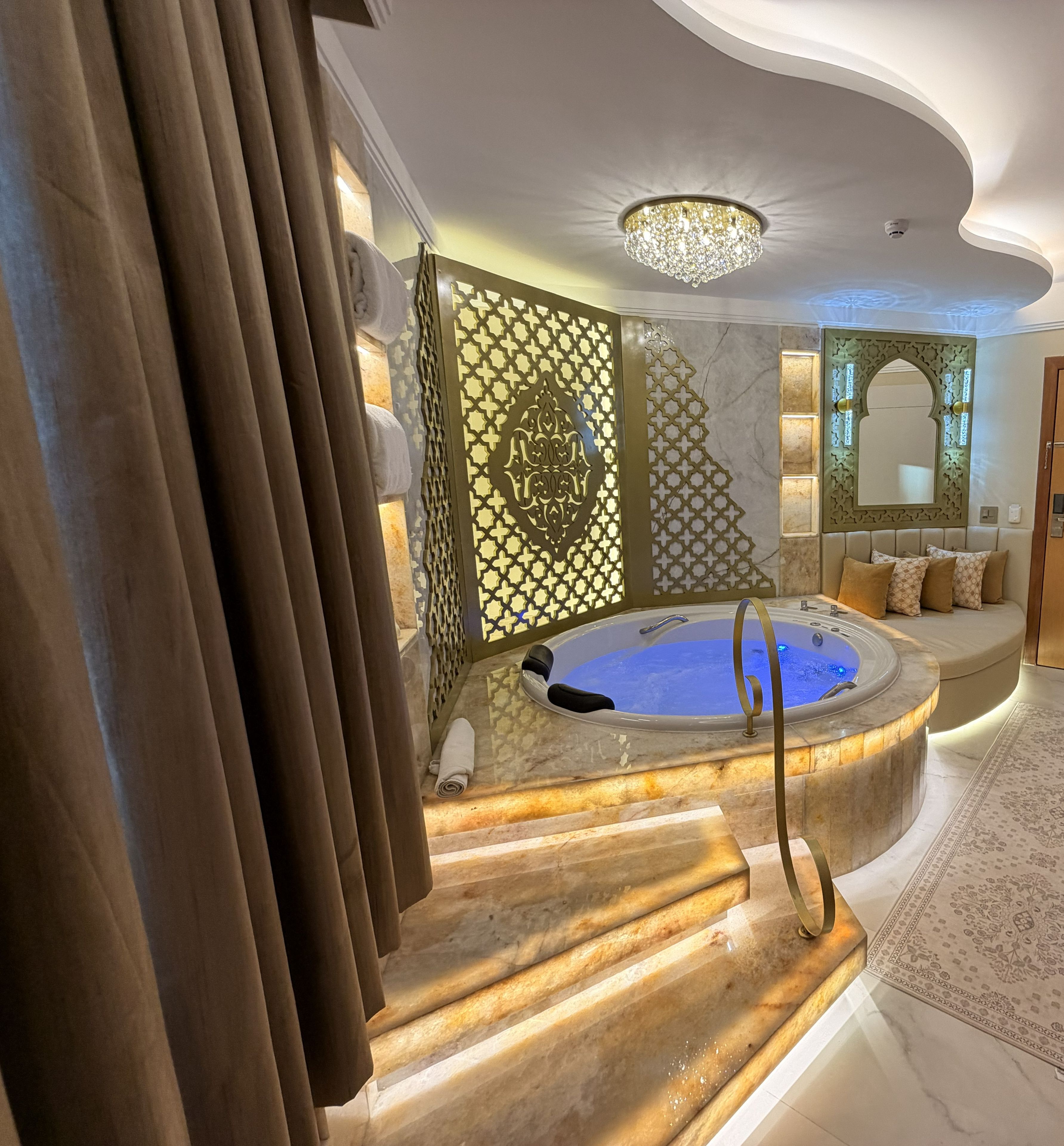 A luxurious bathroom with a marble staircase, a bathtub, and a decorative wall panel.