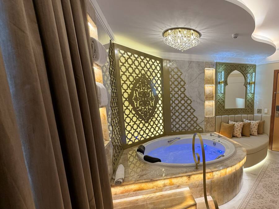 A luxurious bathroom with a marble staircase, a bathtub, and a decorative wall panel.