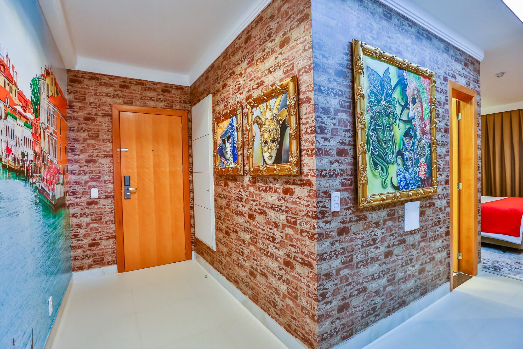 Ein Flur mit Backsteinwand, einer Holztür und zwei gerahmten Kunstwerken.