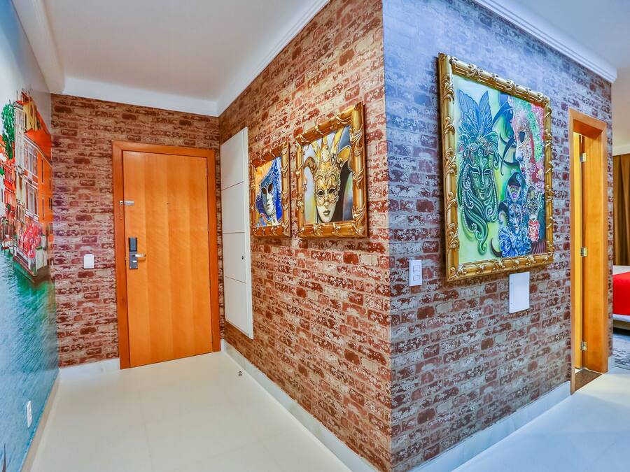 Un pasillo con pared de ladrillo, una puerta de madera y dos cuadros enmarcados.