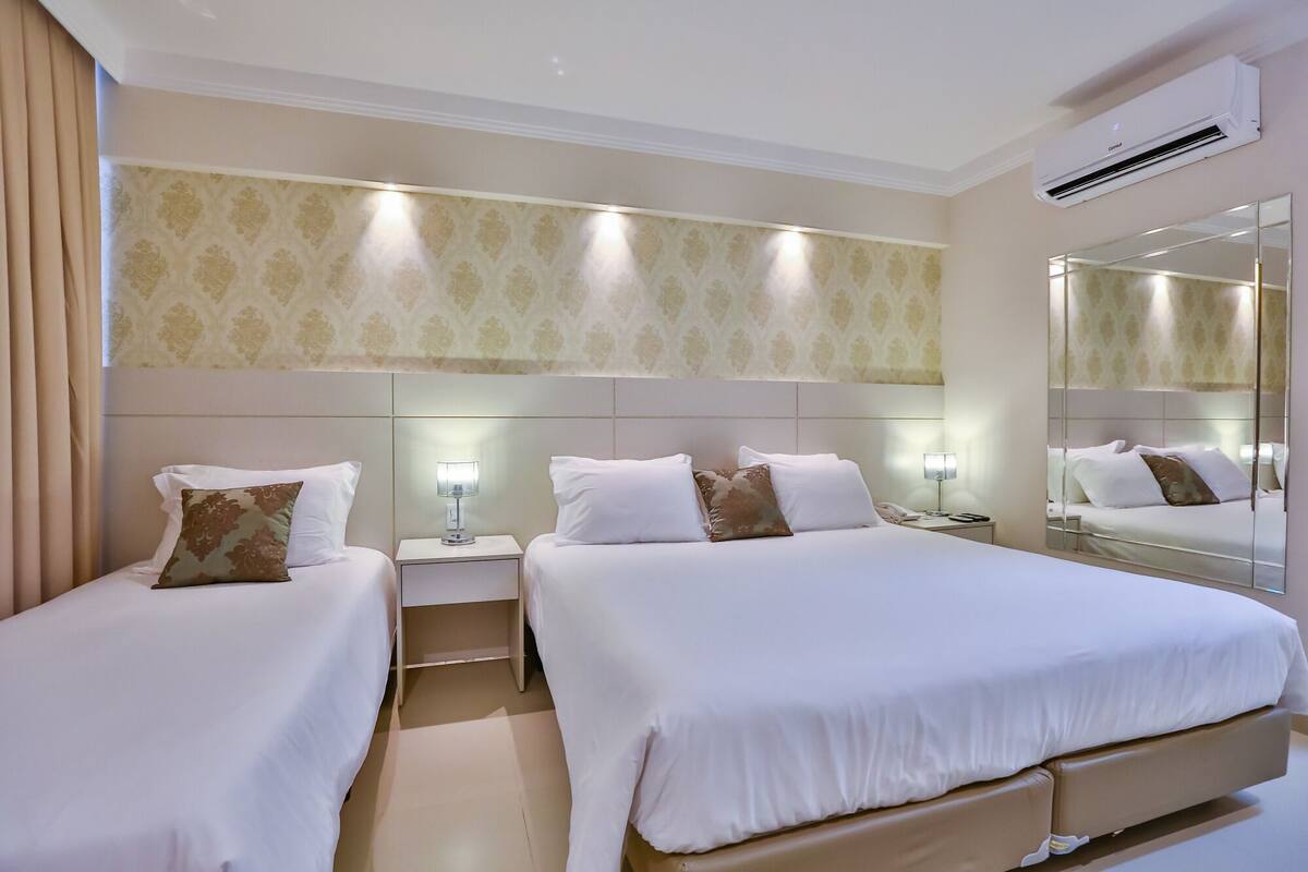Een hotelkamer met twee bedden, een grote spiegel en een airconditioning.
