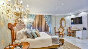 Ein luxuriöses Schlafzimmer mit einem großen Bett, einer Chandelier, einem Schreibtisch und einem Fernseher.