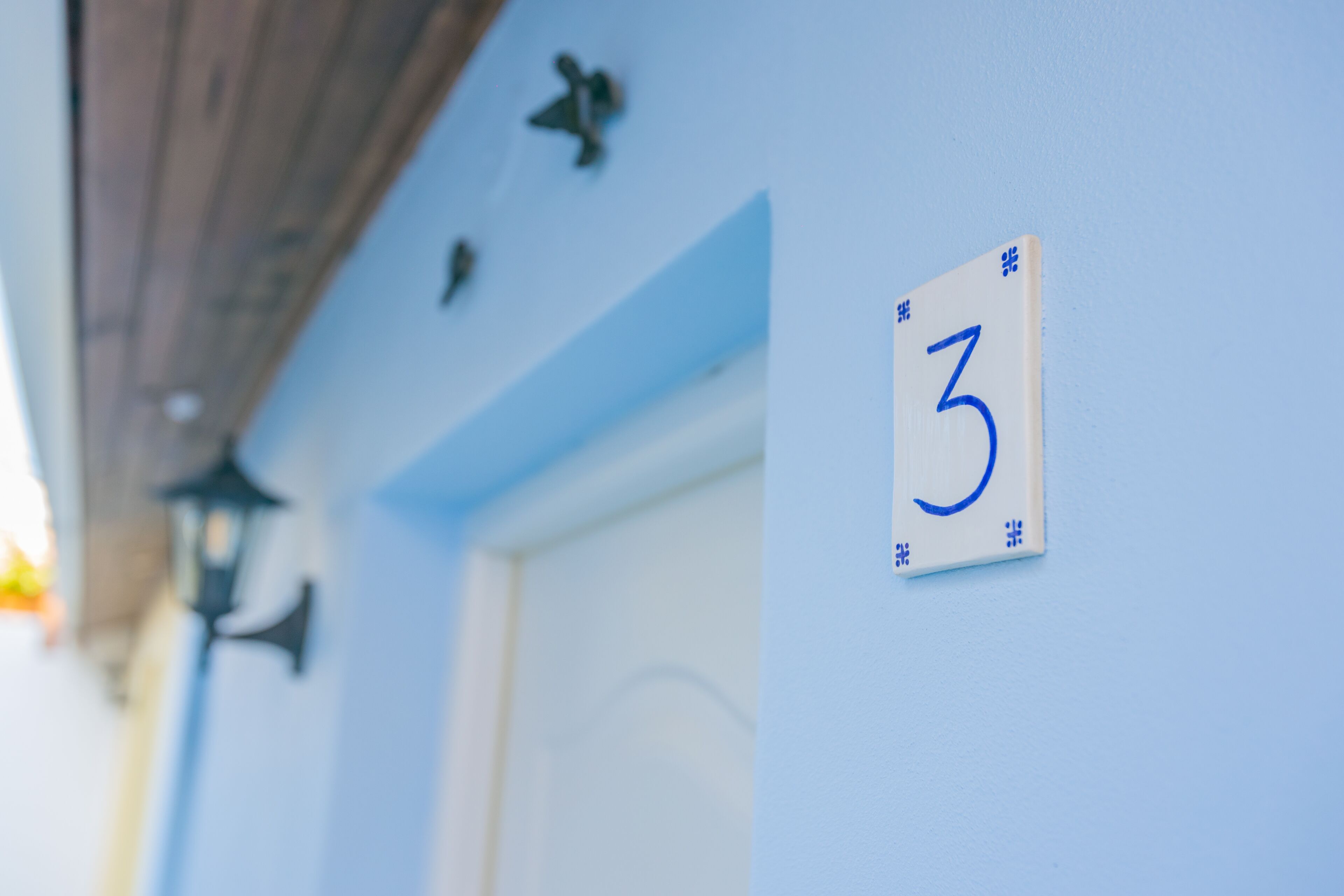 A building exterior with a blue wall, a white door, and a number '3' sign.