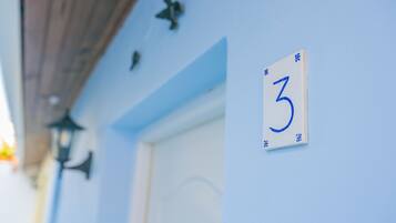 A building exterior with a blue wall, a white door, and a number '3' sign.