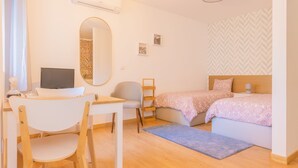 A bedroom with a bed, a desk with a chair, a mirror, and a TV. - Porto Island (Porto)