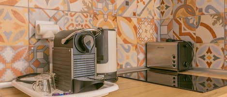 A kitchen with a coffee maker, toaster, and a glass pitcher on the counter.