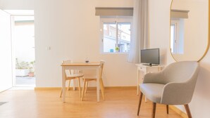 A room with a wooden floor, a dining table with chairs, a television on a stand, and a large mirror on the wall. - Porto Island (Porto)