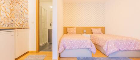 A bedroom with two beds, a wooden headboard, a nightstand, and a patterned wall.