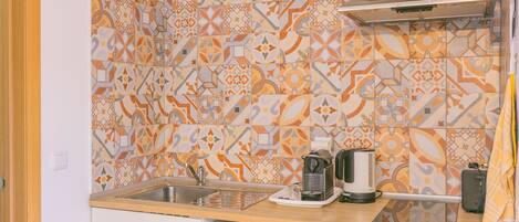 A kitchen with patterned tiles, a sink, a coffee maker, and a toaster.