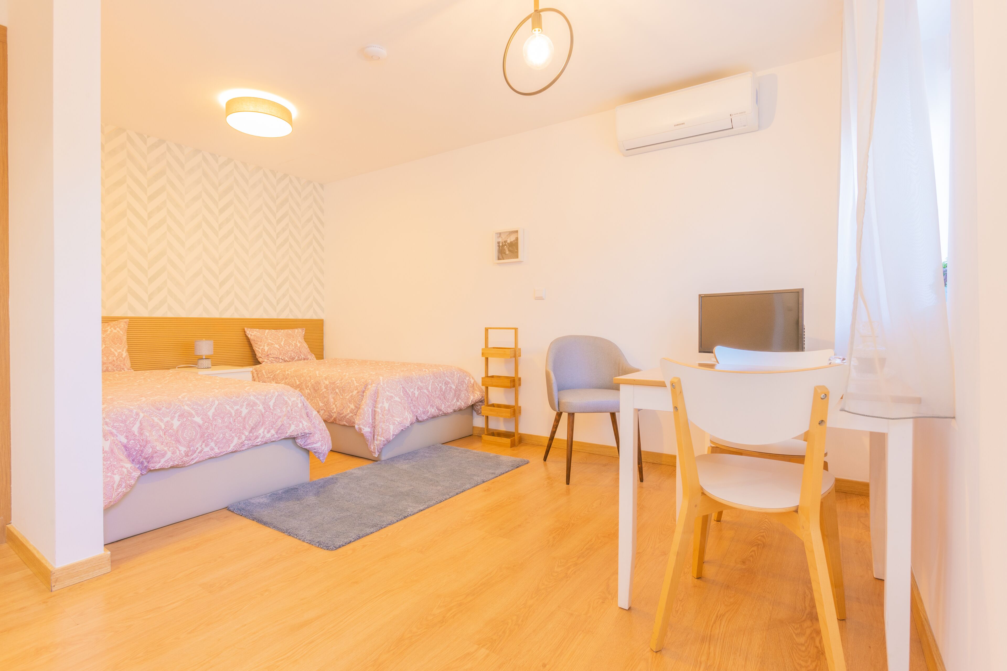 Une chambre avec deux lits, un bureau, une chaise, une télévision et un appareil de climatisation.
