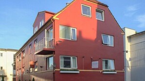 A red multi-story residential building with balconies, windows, and a garage door. - Stavanger Bed & Breakfast (Stavanger)
