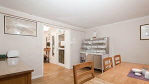 A modern kitchen with a built-in refrigerator, wooden dining table, and chairs. - Stavanger Bed & Breakfast (Stavanger)
