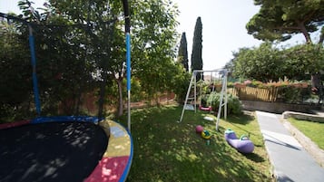 A backyard with a trampoline, a swing set, and a small garden area.