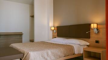 Una habitación de hotel con una cama, mesitas de noche y lámparas de pared.