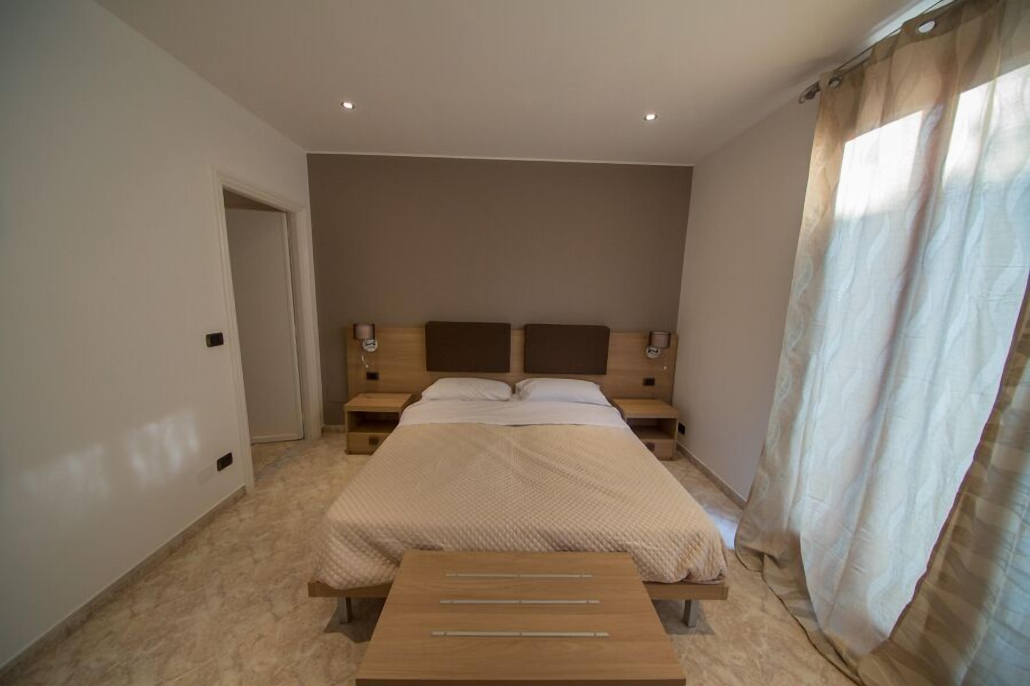 A bedroom with a bed, bedside tables, and a wooden bench.