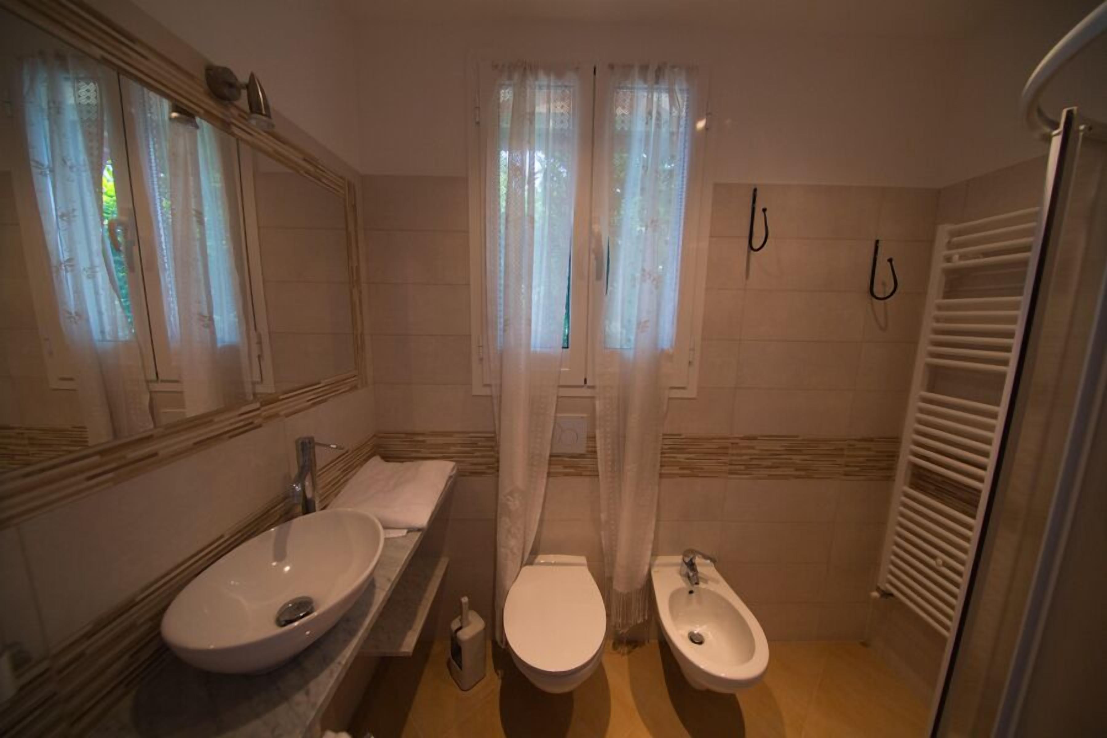 Un baño con lavamanos, inodoro, bidé y espejo.
