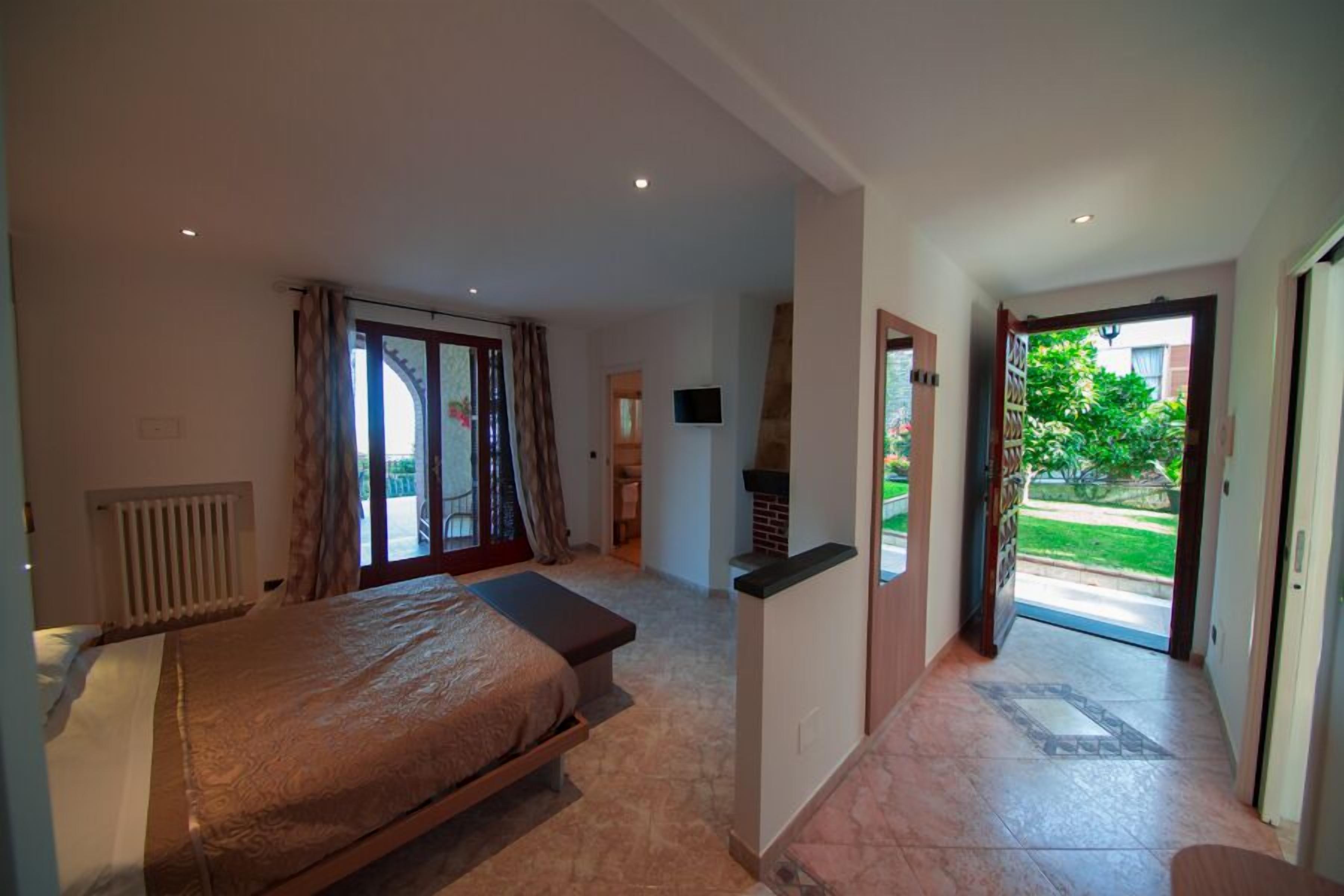 A bedroom with a bed, a radiator, a television, and a view of the outdoors.