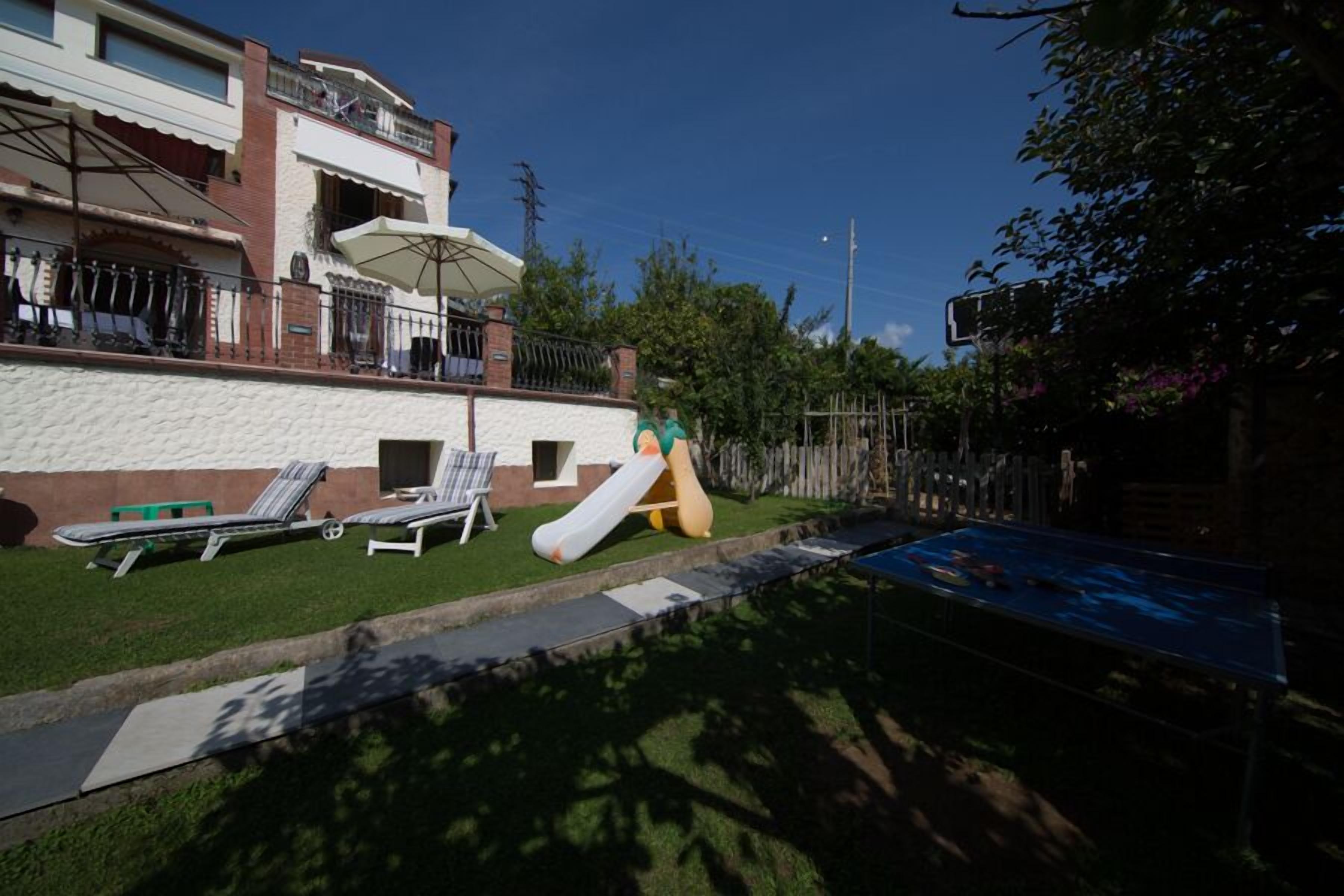 A residential area with a swimming pool, lounge chairs, and a slide.