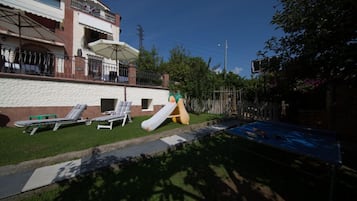 A residential area with a swimming pool, lounge chairs, and a slide.