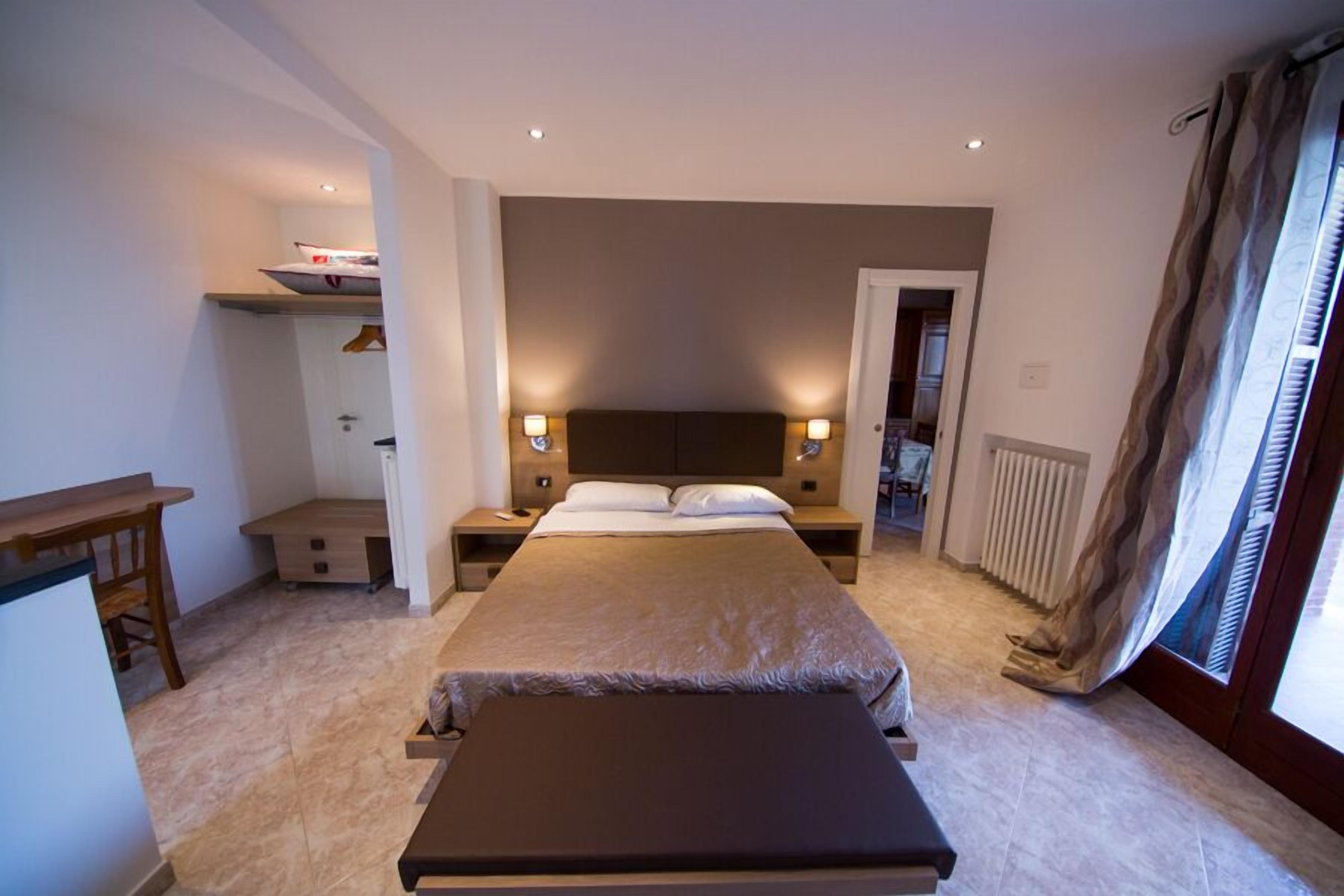 Une chambre à coucher avec un grand lit, des tables de chevet, un bureau et un radiateur.