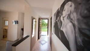 A hallway with a tiled floor, a large black and white portrait on the wall, and a door leading to an outdoor area. - La Dolce Vita (Taggia)