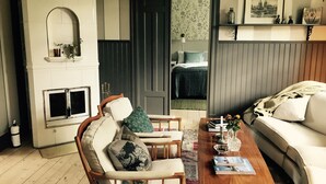 Una sala de estar con chimenea, un sofá, una mesa de centro y una silla.