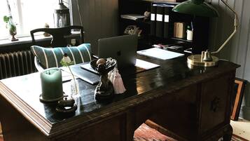 A wooden desk with a laptop, a green desk lamp, and various decorative items.