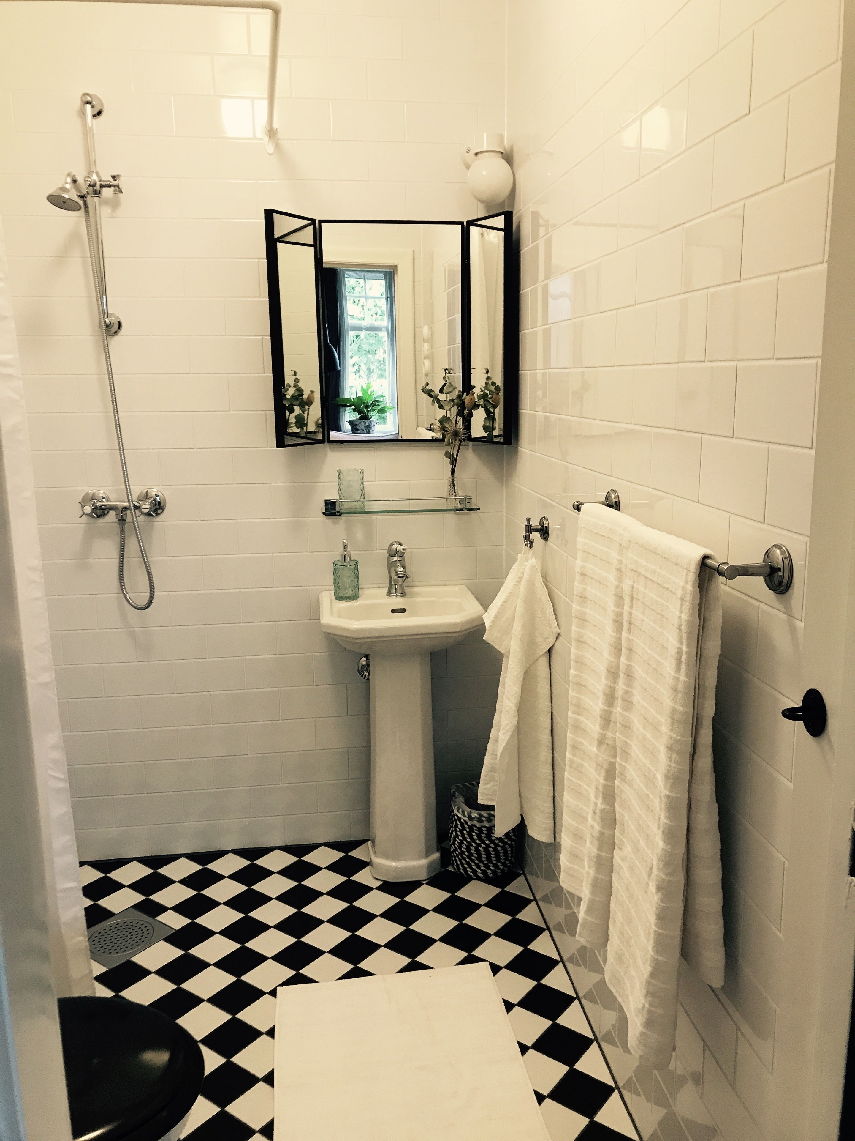 A bathroom with a black and white checkered floor, a white sink, a mirror, and a towel rack.