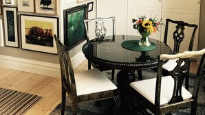 Un comedor con una mesa redonda, sillas y una araña.