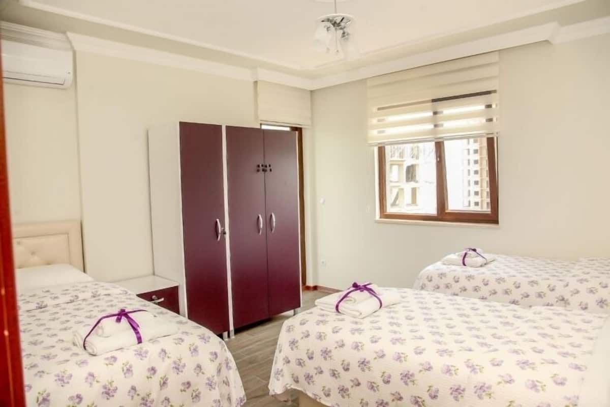 A hotel room with two beds, a wardrobe, and a window with blinds.