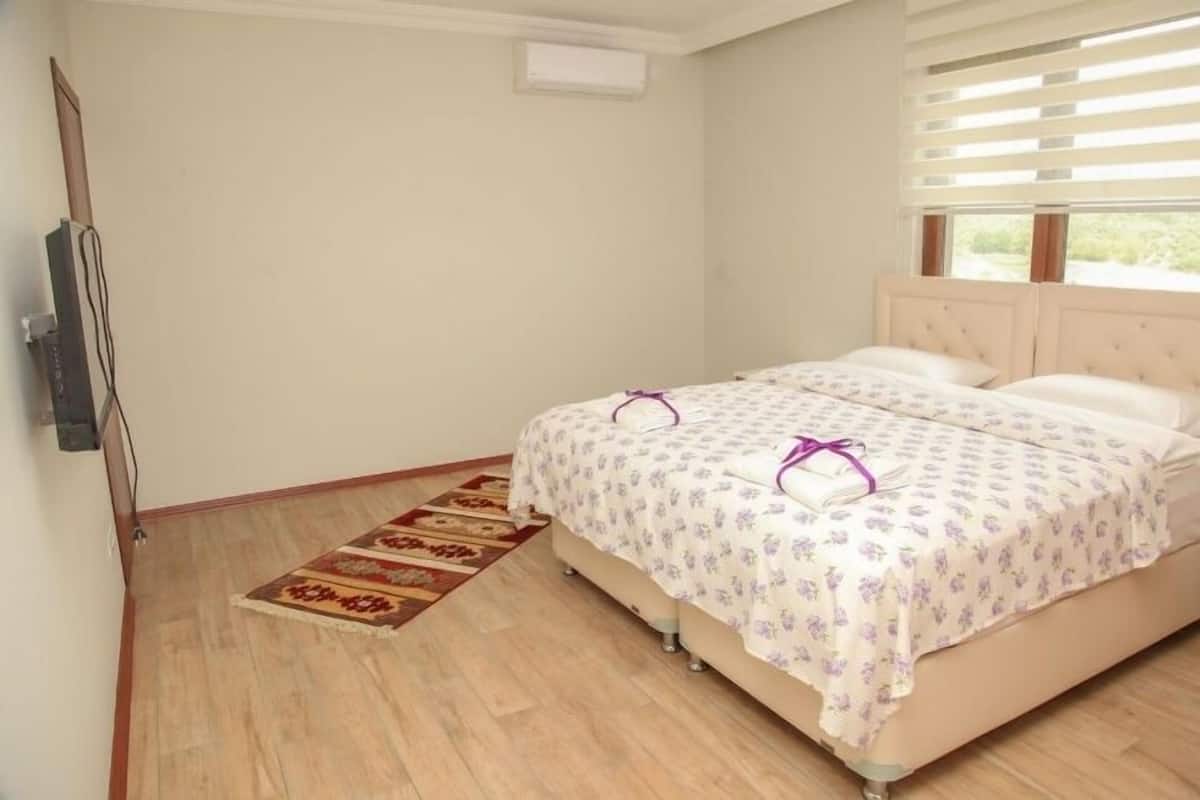 A bedroom with a bed, a TV, and a window with blinds.