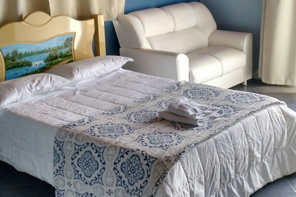 A bedroom with a bed, a sofa, and curtains.