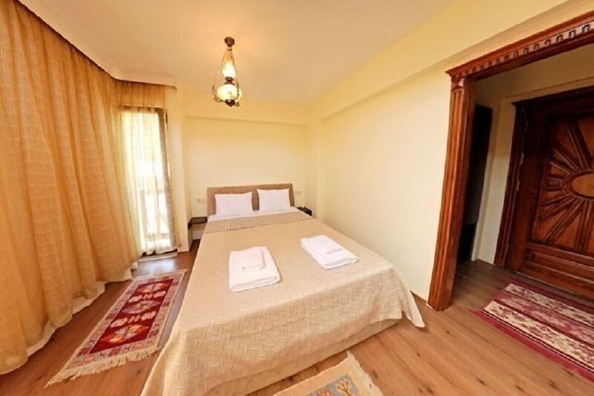 A hotel room with a bed, curtains, a chandelier, and a wooden door.