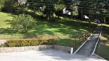 A concrete staircase leading up to a grassy area with a stone wall and a wooden fence.