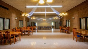 A spacious dining area with brick walls, multiple wooden tables and chairs, and pendant lighting. - Lafayette Inn (Moundsville)