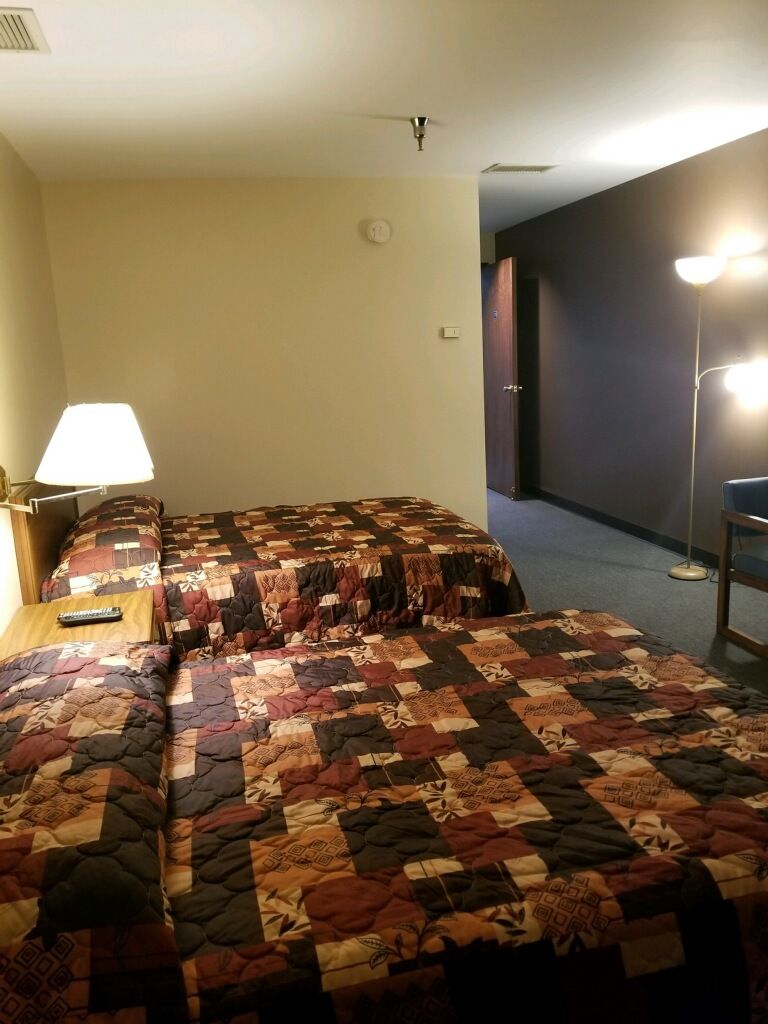 Ein Hotelzimmer mit zwei Betten, einem Nachttisch, einer Lampe und einer Stehlampe.